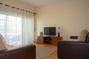 uma sala de estar com uma televisão de ecrã plano e 2 cadeiras em Vizinha’s Dad’s Apartment em Ponta Delgada