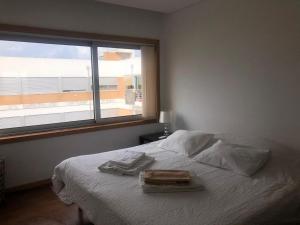 um quarto com uma cama branca e uma janela em Zurstrassen Apartment em Coimbra