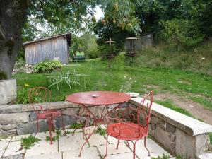 une table et des chaises rouges dans un jardin dans l'établissement Les Folies de la Serve, à Ouroux