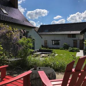 un jardín con sillas rojas y una mesa frente a una casa en WE Maison d'hôtes en Cassel