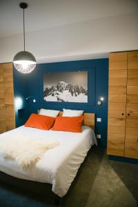 - une chambre bleue dotée d'un grand lit avec des oreillers orange dans l'établissement Appart'Hotel Aiguille Verte & Spa, à Chamonix-Mont-Blanc