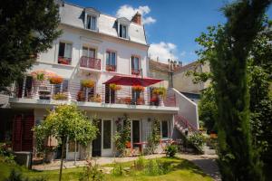 a white building with flower boxes and an umbrella at Le Jardin des Toiles in Triel-sur-Seine