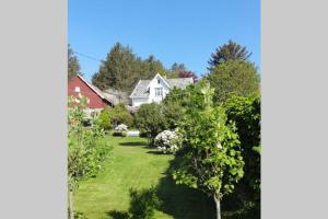 uma vista para um quintal com árvores e uma casa em Charming flat in cosy farmhouse em Skudeneshavn