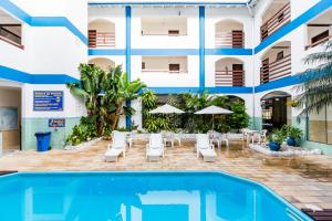 a hotel with a pool and chairs and a building at HsHotelaria - Filial Bombinhas in Bombinhas