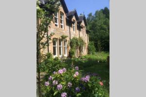una vecchia casa con dei fiori davanti di The Loft at Craiglea a Pitlochry