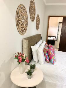 Una cama con almohadas blancas y una mesa con flores. en Pousada do Pescador, en Penha