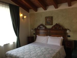 1 dormitorio con 1 cama con cabecero de madera y ventana en Casa San Marco, en Castelnuovo del Garda
