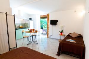 a room with a bed and a kitchen with a table at Villa Les Lieges de Palombaggia in Porto-Vecchio