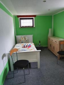 Schlafzimmer mit grünen Wänden und einem Bett mit einem Schreibtisch in der Unterkunft Zimmervermietung Cottbusser Ostsee in Cottbus