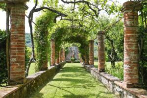 un arco in un giardino con erba e alberi di Villa Le Cipresse a San Quirico di Moriano
