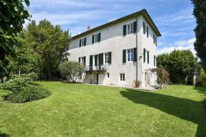 una grande casa bianca con un ampio cortile di Villa Le Cipresse a San Quirico di Moriano