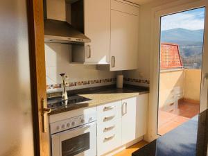 cocina con armarios blancos y vistas a un balcón en Aticos La Aliseda by Valdesierra, en Béjar