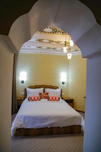 a bedroom with a large white bed with red pillows at Old Gate Hotel in Bukhara