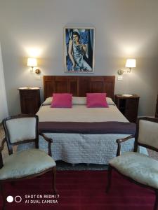 een slaapkamer met een bed met roze kussens en 2 stoelen bij VILLA ANTONIETTA in Cesenatico