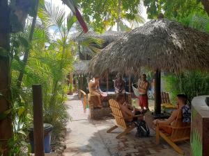 a group of people sitting in chairs under a straw umbrella at Tower Bridge Hostel in Puerto Escondido