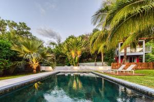 a swimming pool in the backyard of a house with palm trees at Tipalais in Saint-Pierre
