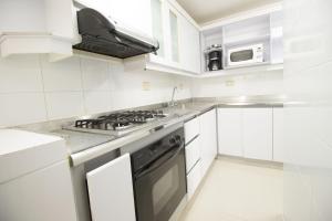 cocina blanca con fogones y microondas en San Fernando Suite 202 - Livin Colombia, en Cali