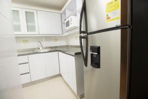 cocina con armarios blancos y nevera en San Fernando Suite 202 - Livin Colombia, en Cali
