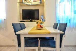 a white table with chairs and a bowl of fruit on it at Apartments Tanga in Rovinj