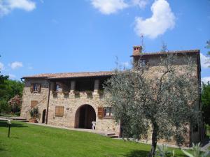 un gran edificio de piedra con un árbol delante de él en Agriturismo Casagrande, en Montepulciano