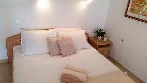 1 dormitorio con 1 cama blanca y 2 almohadas en Guesthouse Iva en Hvar