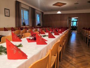 Hotel Mauernböck في Rottenbach: قاعة اجتماعات مع طاولة طويلة مع مناديل حمراء