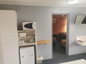 a room with a microwave and a room with a bed at Central Motel Ipswich in Ipswich