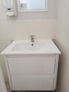 lavabo blanco en el baño con espejo en Central Motel Ipswich, en Ipswich