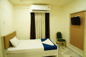une chambre d'hôtel avec un lit et une chaise dans l'établissement Hotel Swagath Grand Miryalaguda, à Miriālgūda