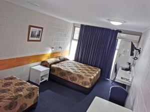 a small room with two beds and a table at Central Motel Ipswich in Ipswich