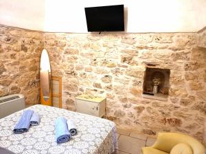 Habitación con mesa y TV en una pared de piedra. en Trullo Madia e Dimora Giorgio, en Ceglie Messapica