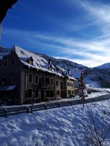 un edificio en la nieve con una calle cubierta de nieve en Alojamiento Rural Ostau Era Nheuada, en Aubert