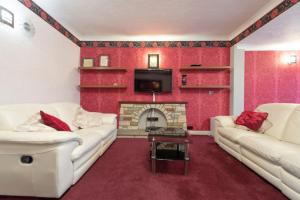 a living room with two white couches and a fireplace at Spacious Bungalow in Romford with parking in Romford