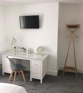 a white desk with a chair and a tv on a wall at Glenthorne Guest House in Tenby