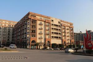 a large building with cars parked in a parking lot at Luxurious Landing Apartments & Suites Bahria Town in Rawalpindi