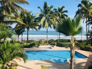 a swimming pool with palm trees and the beach at Precioso Dpto a 20m de la playa Con Aire Acondicionado en Ambos Dormitorios Club Casablanca in Same