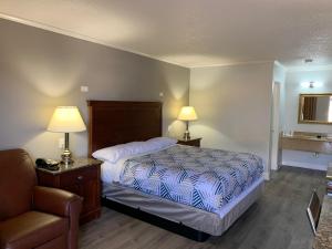 ein Schlafzimmer mit einem Bett, einem Stuhl und zwei Lampen in der Unterkunft Motel 6 Newport News, VA – Fort Eustis in Newport News