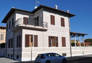 a white building with a car parked in front of it at Villa Salvini in Marina di Pisa