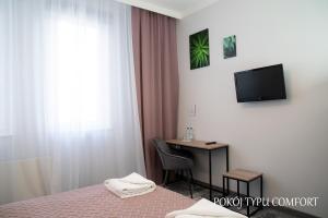 a hotel room with a bed and a desk and a television at Baron in Ciechanów
