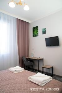 Habitación de hotel con 2 camas, escritorio y TV. en Baron, en Ciechanów