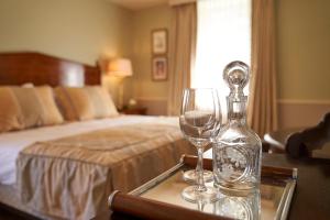a bedroom with a bed and two wine glasses on a table at HOTEL Les Contes de Bruyeres in Servières-le-Château