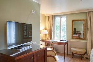 a hotel room with a large television and a desk at HOTEL Les Contes de Bruyeres in Servières-le-Château