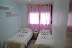 two beds in a room with a pink curtain at SAMSA House in Águilas