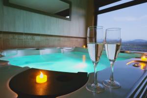 two glasses of wine and a candle on a table with a hot tub at Casa Rural & SPA Mirador de la Covatilla in Guijo de Ávila