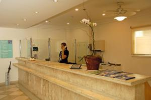 a woman standing behind a counter in a room at Vitória Hotel Residence NewPort in Campinas