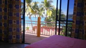 a bedroom with a view of the ocean from a balcony at Pie de Playa la Ropa in Zihuatanejo