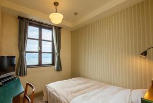 a bedroom with a bed and a desk and a window at Kitabiwako Hotel Grazie in Nagahama