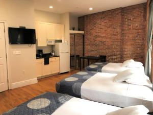 Una habitación con dos camas y una cocina con pared de ladrillo. en Studios Midtown Manhattan, en Nueva York