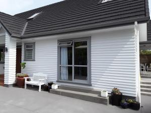 a white house with a white bench on a porch at Suite Petite in Taupo