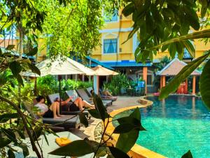 a group of people laying on lounge chairs next to a swimming pool at Central Privilege Hotel in Siem Reap